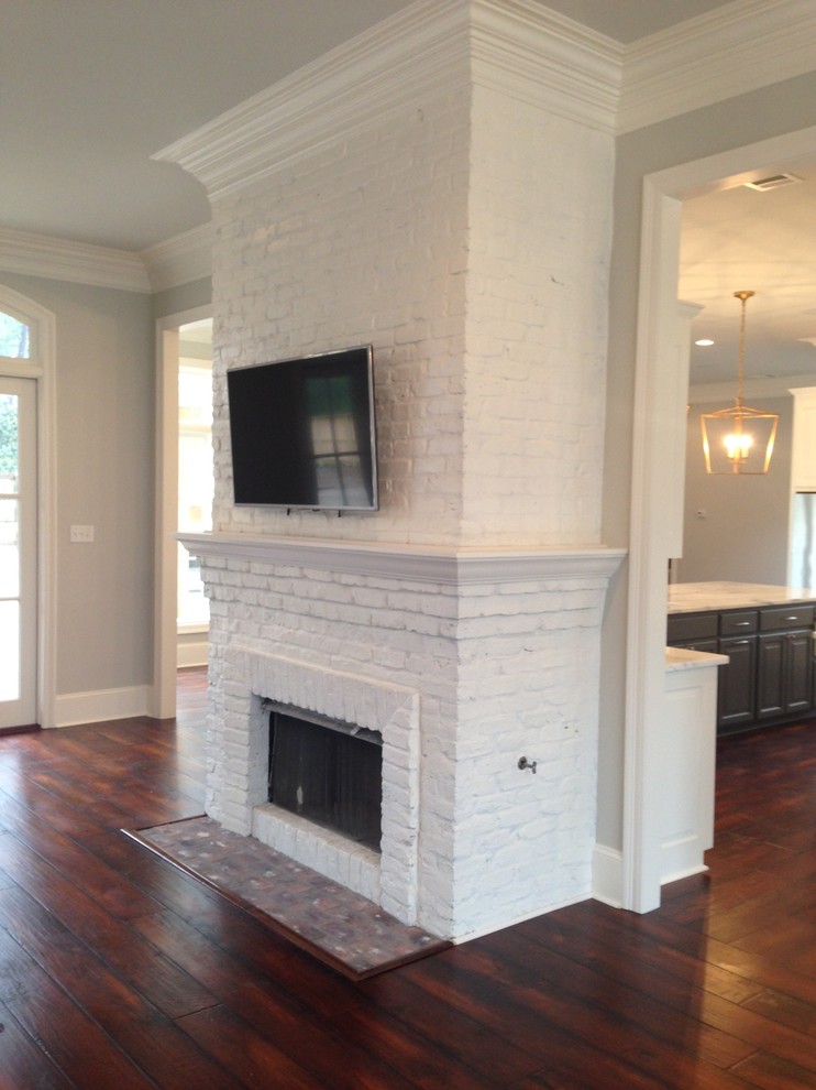 Inspiration for a large classic open plan games room in New Orleans with a home bar, grey walls, dark hardwood flooring, a standard fireplace, a brick fireplace surround and a wall mounted tv.