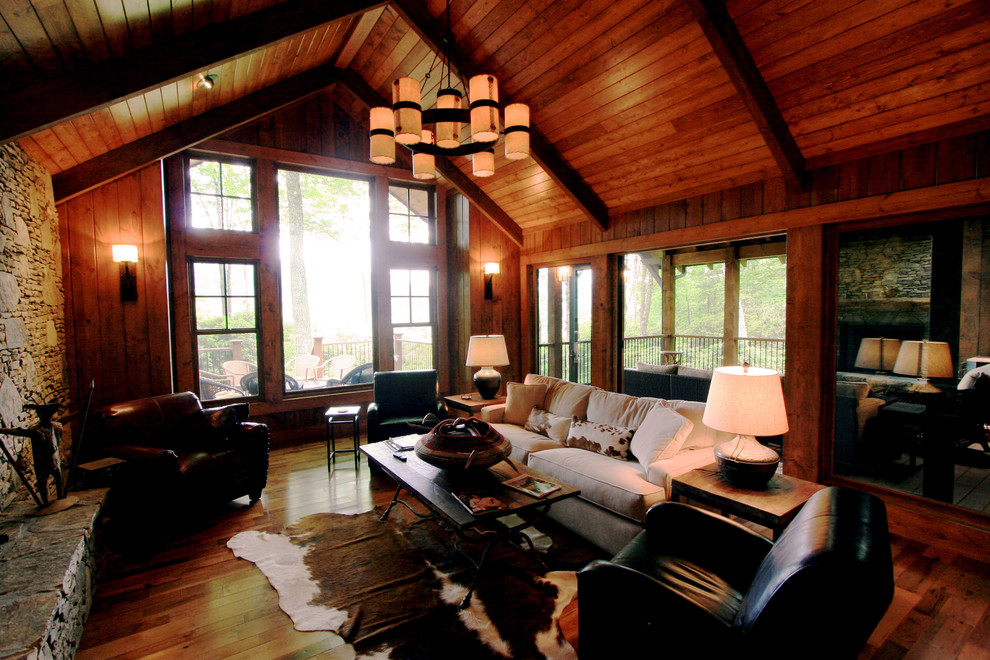 Imagen de sala de estar abierta tradicional grande con paredes marrones, suelo de madera oscura, todas las chimeneas y marco de chimenea de piedra