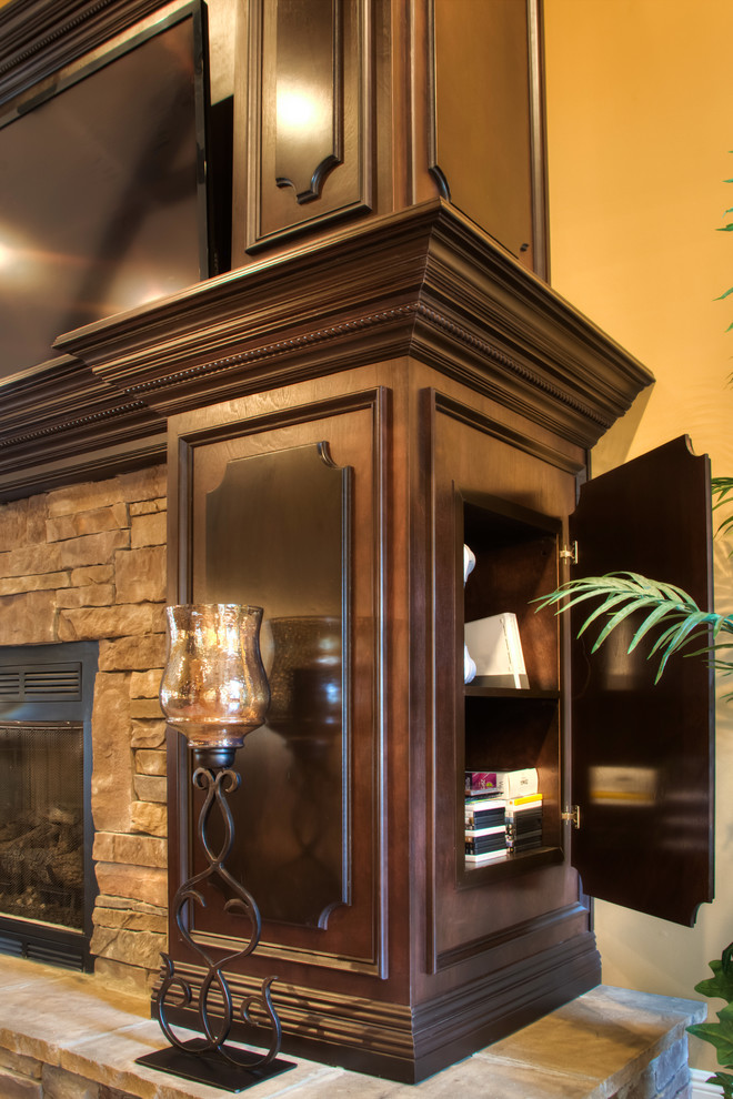 Diseño de sala de estar abierta tradicional con televisor colgado en la pared, paredes marrones, suelo de madera en tonos medios, todas las chimeneas y marco de chimenea de piedra