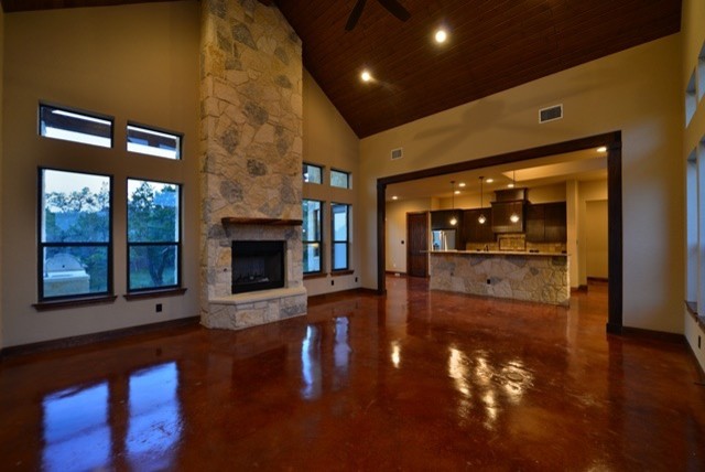Mittelgroßes, Offenes, Fernseherloses Modernes Wohnzimmer mit Betonboden, Kamin, Kaminumrandung aus Stein und beiger Wandfarbe in Austin