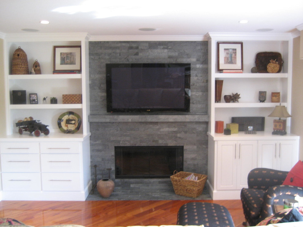 Diseño de sala de estar cerrada tradicional de tamaño medio con paredes grises, suelo de madera en tonos medios, todas las chimeneas, marco de chimenea de piedra y televisor colgado en la pared
