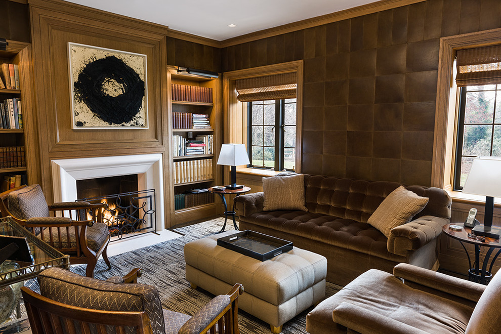 На фото: гостиная комната в современном стиле с с книжными шкафами и полками, коричневыми стенами, стандартным камином и коричневым диваном с