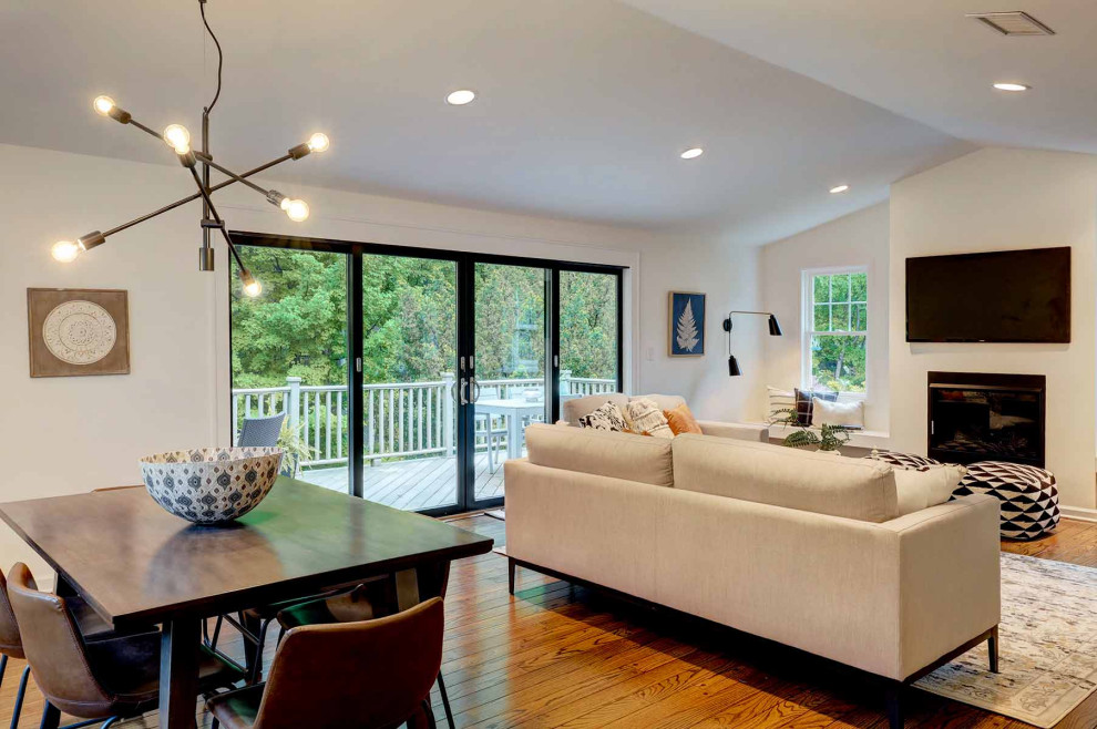 Esempio di un grande soggiorno moderno aperto con pareti bianche, pavimento in legno massello medio, cornice del camino in intonaco e TV a parete