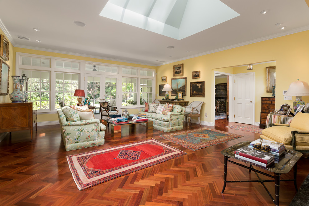 Imagen de sala de estar tradicional con paredes amarillas y suelo de madera en tonos medios