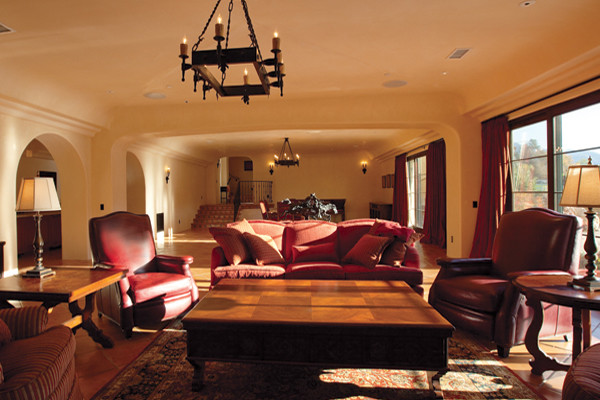 フェニックスにあるラグジュアリーな地中海スタイルのおしゃれなファミリールーム (テラコッタタイルの床、コーナー設置型暖炉、タイルの暖炉まわり、ベージュの壁、埋込式メディアウォール) の写真