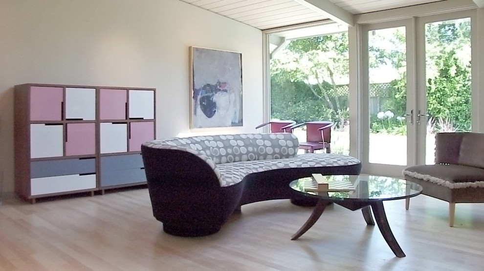Ejemplo de sala de estar abierta vintage de tamaño medio sin chimenea con paredes beige, suelo de madera clara y pared multimedia