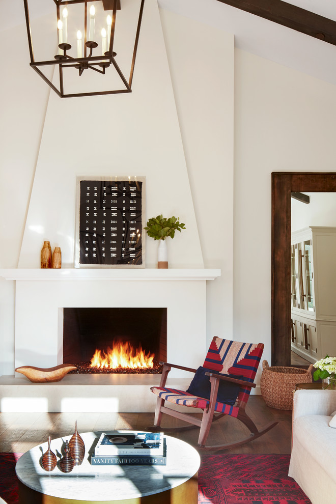 Diseño de sala de estar mediterránea con suelo de madera oscura y marco de chimenea de yeso