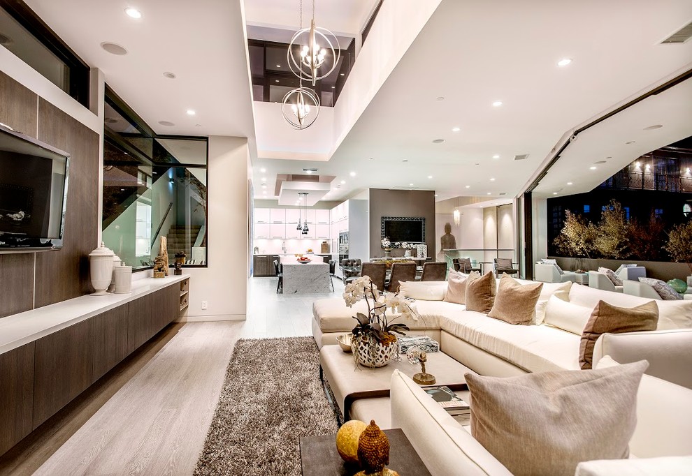 Immagine di un grande soggiorno minimal aperto con pareti bianche, pavimento in legno massello medio e TV a parete