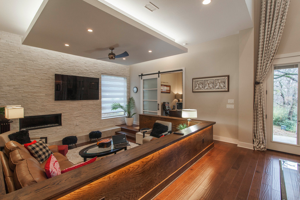 This is an example of a medium sized contemporary enclosed games room in Dallas with grey walls, medium hardwood flooring, a ribbon fireplace and a stone fireplace surround.