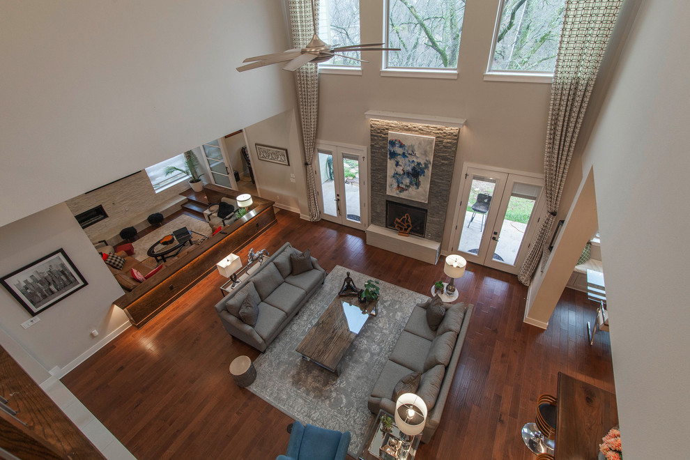 Modernes Wohnzimmer mit grauer Wandfarbe, braunem Holzboden, Kamin und Kaminumrandung aus Stein in Dallas