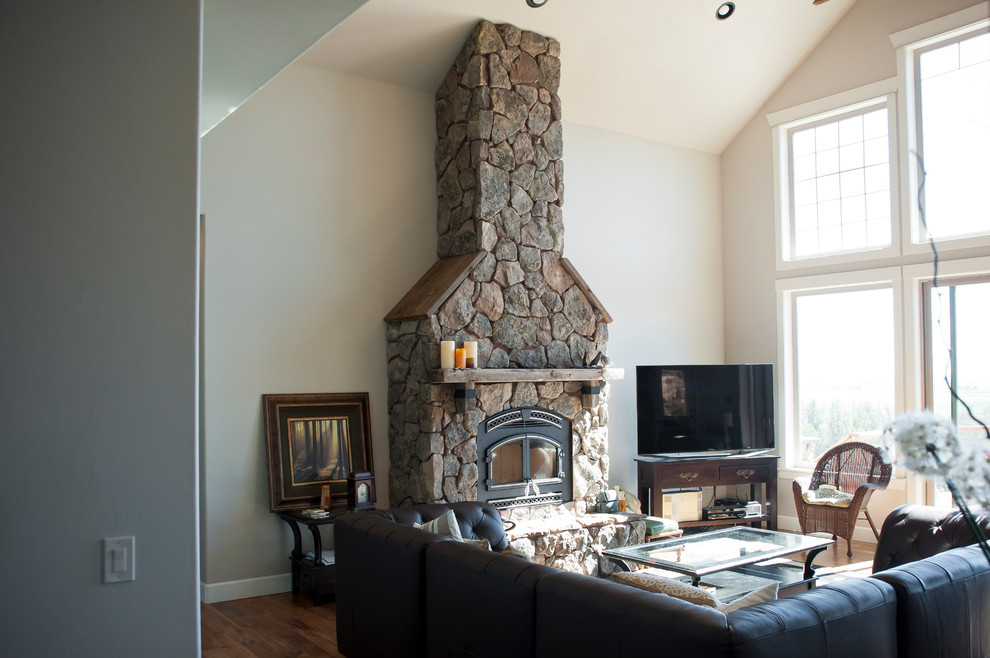 Imagen de sala de estar abierta rural de tamaño medio sin televisor con paredes blancas, suelo de madera en tonos medios, todas las chimeneas, marco de chimenea de piedra y suelo marrón