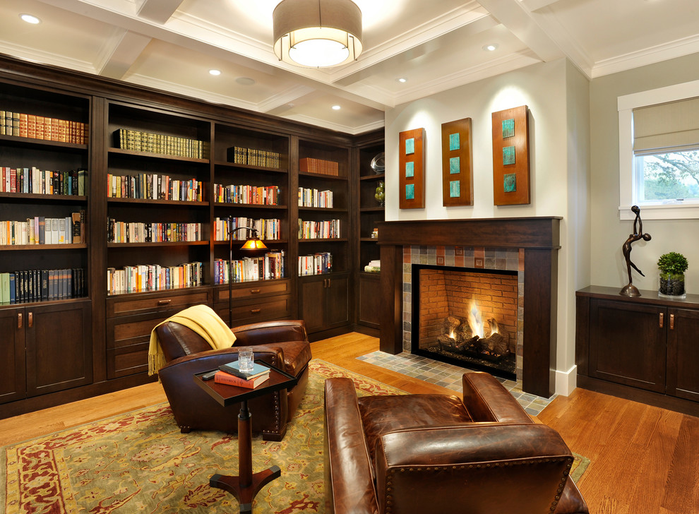 На фото: гостиная комната в современном стиле с с книжными шкафами и полками, фасадом камина из плитки и ковром на полу с