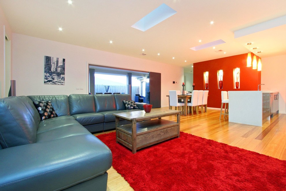Esempio di un grande soggiorno design aperto con pareti rosse, parquet chiaro, parete attrezzata e pavimento marrone