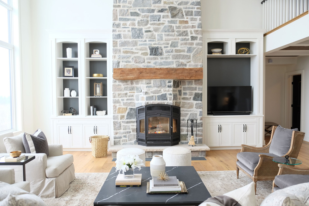 Inspiration for a farmhouse open plan games room in Toronto with white walls, light hardwood flooring, a stone fireplace surround, a freestanding tv and a wood burning stove.