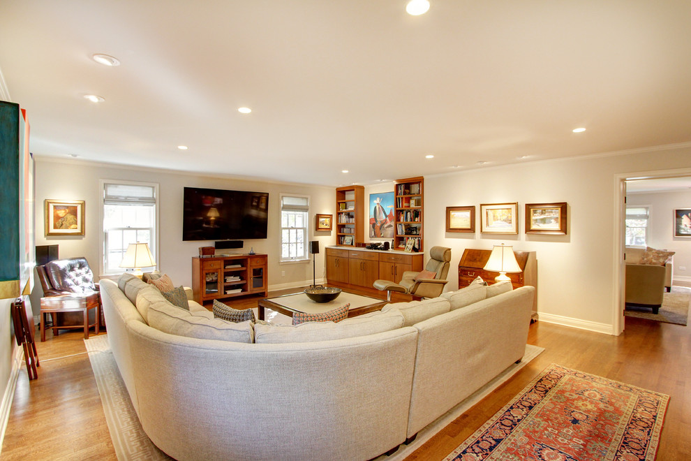 Diseño de sala de estar abierta clásica renovada de tamaño medio sin chimenea con paredes beige, suelo de madera clara, televisor colgado en la pared y suelo marrón