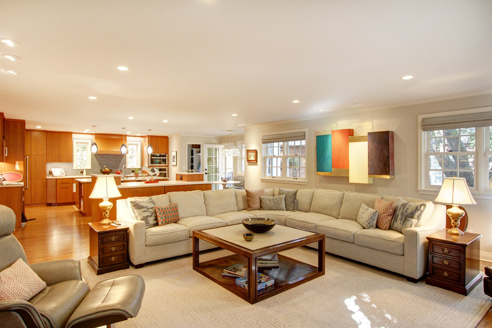 Modelo de sala de estar abierta tradicional renovada de tamaño medio sin chimenea con paredes beige, suelo de madera clara, televisor colgado en la pared y suelo marrón