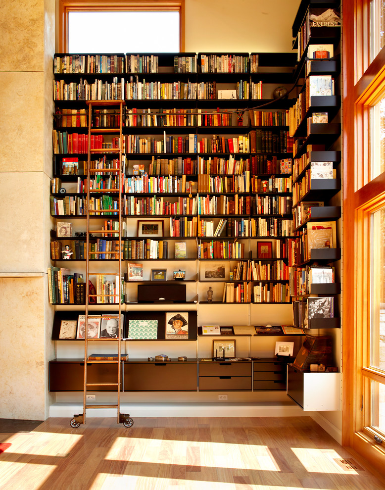 Inspiration pour une très grande salle de séjour design avec une bibliothèque ou un coin lecture, parquet clair, un mur blanc et un sol marron.