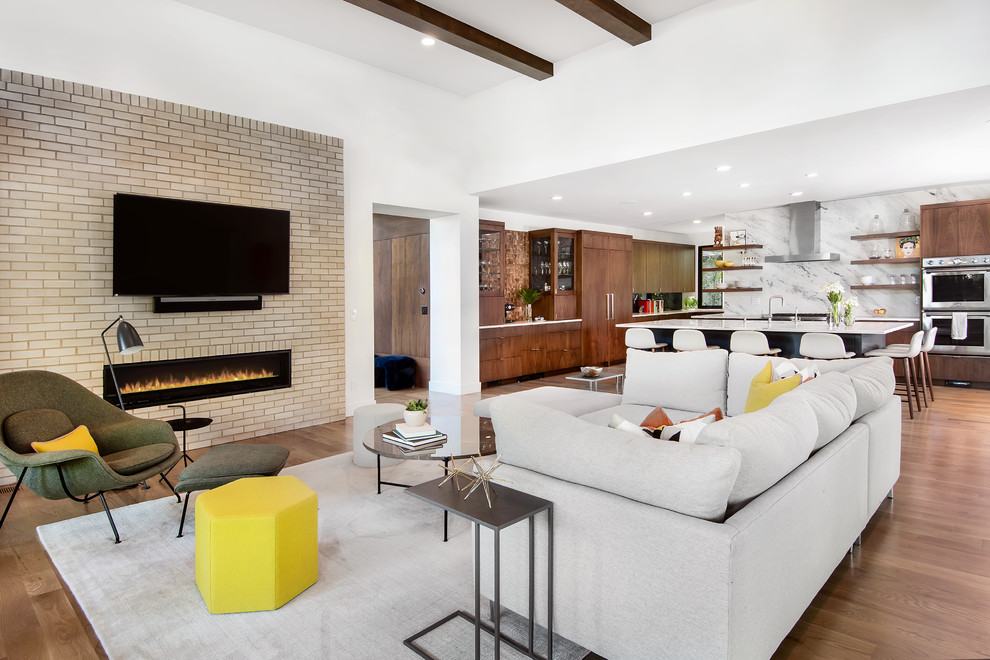 Offenes Retro Wohnzimmer mit weißer Wandfarbe, braunem Holzboden, Gaskamin, TV-Wand und Kaminumrandung aus Backstein in Denver