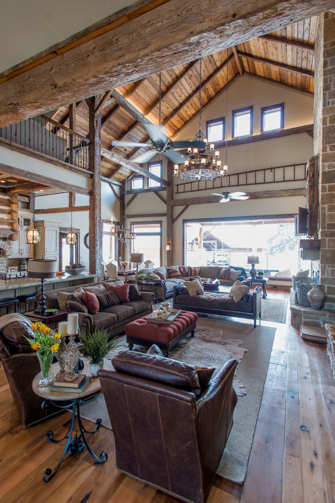 Inspiration for a large rustic open plan games room in Houston with beige walls, medium hardwood flooring, a standard fireplace, a stone fireplace surround, a built-in media unit and brown floors.