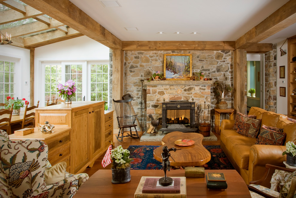 Imagen de sala de estar tradicional sin televisor con paredes blancas, suelo de madera en tonos medios, todas las chimeneas y marco de chimenea de piedra
