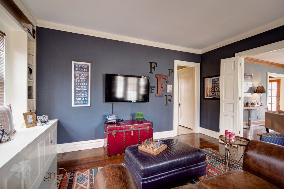 Aménagement d'une salle de séjour classique de taille moyenne et fermée avec une bibliothèque ou un coin lecture, un mur bleu, un sol en bois brun et un téléviseur fixé au mur.