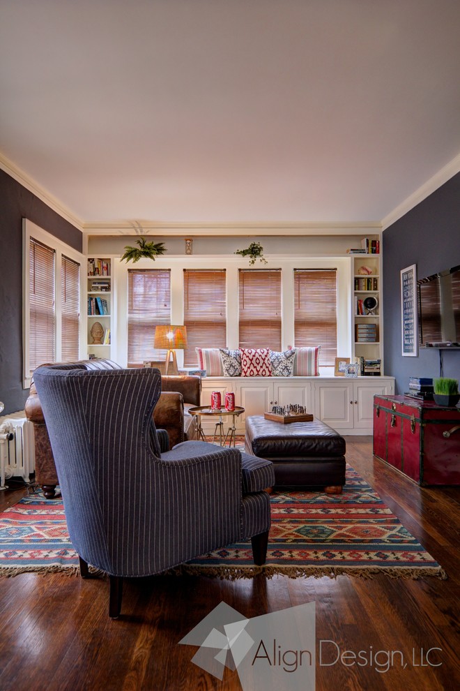 Cette image montre une salle de séjour traditionnelle de taille moyenne et fermée avec une bibliothèque ou un coin lecture, un mur bleu, un sol en bois brun et un téléviseur fixé au mur.