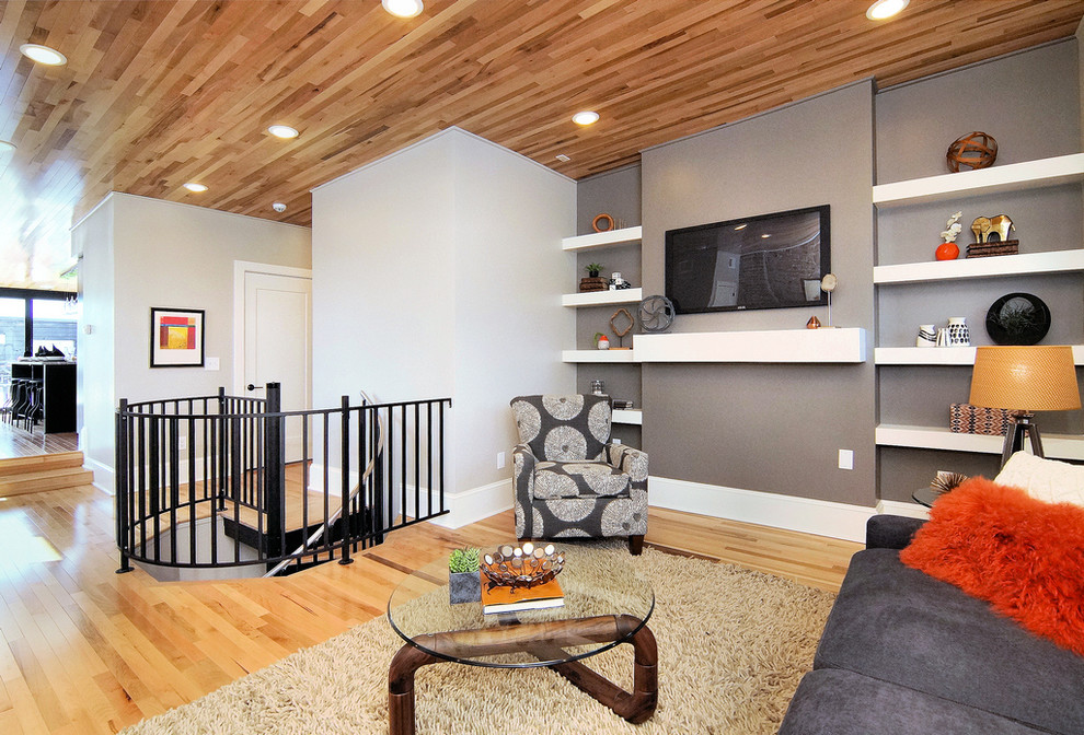 Foto di un soggiorno design di medie dimensioni e stile loft con pareti grigie, parquet chiaro, TV a parete, nessun camino e pavimento beige