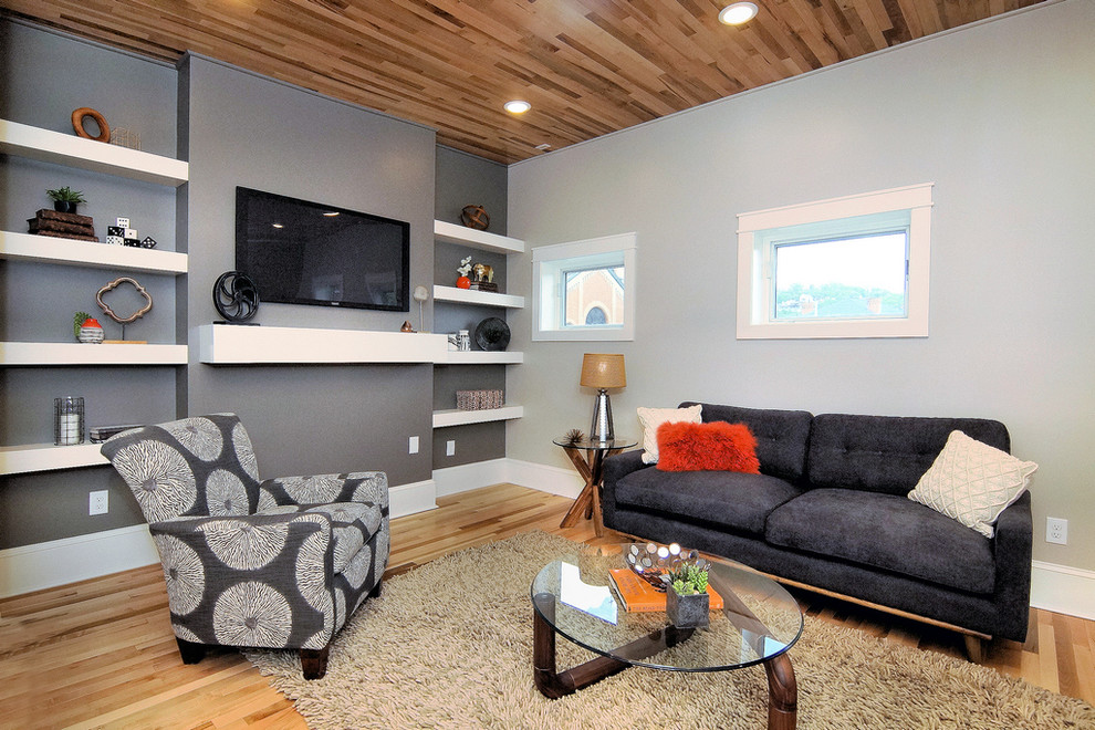 Imagen de sala de estar cerrada contemporánea de tamaño medio sin chimenea con paredes grises, suelo de madera clara, televisor colgado en la pared y suelo beige