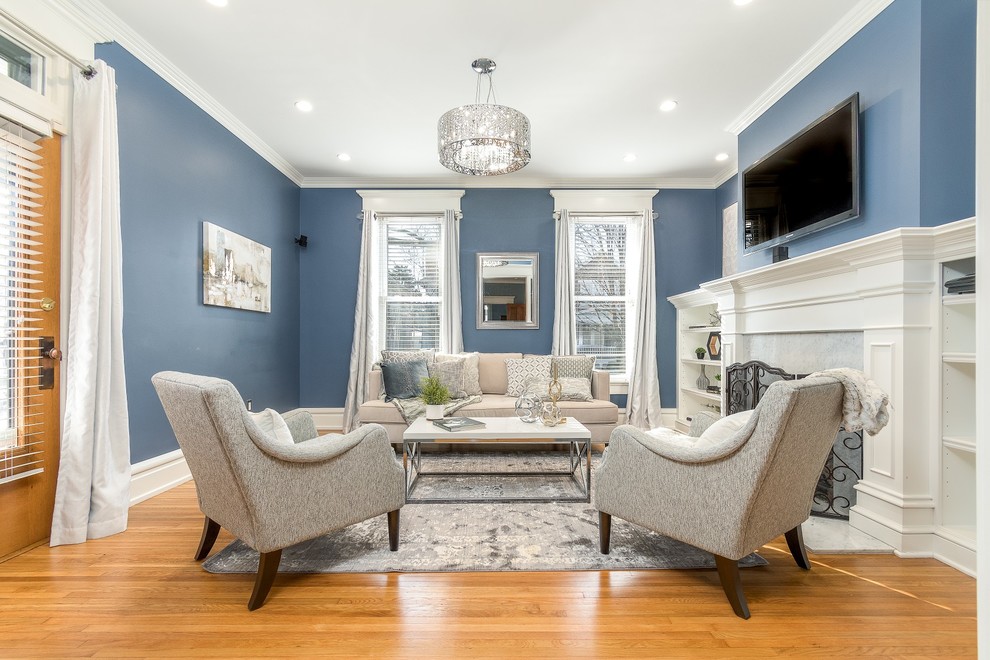 Foto di un soggiorno classico di medie dimensioni e chiuso con pareti blu, camino classico, TV a parete, pavimento in legno massello medio e pavimento beige