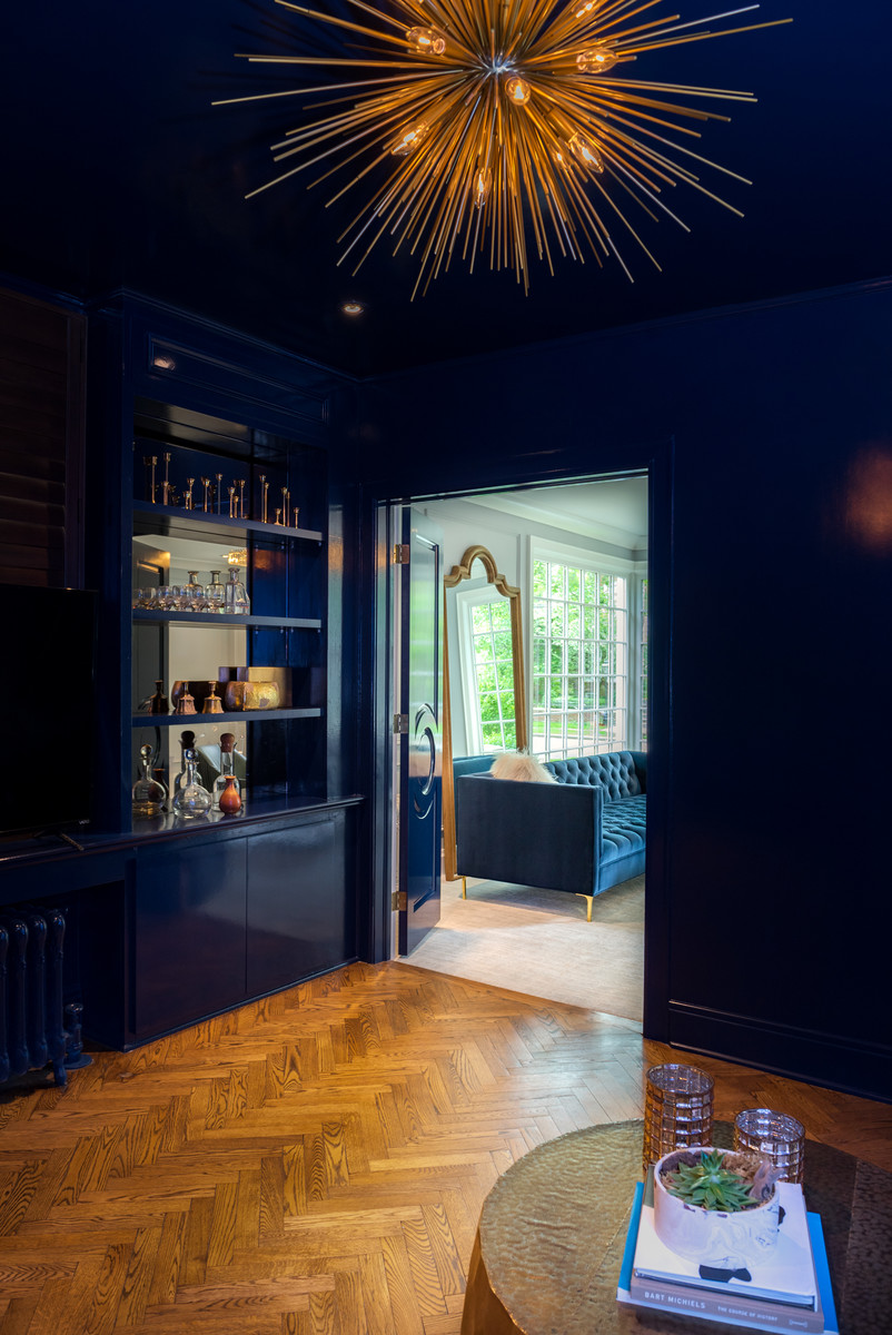 Mittelgroßes, Abgetrenntes Modernes Wohnzimmer mit Hausbar, blauer Wandfarbe, braunem Holzboden, freistehendem TV und braunem Boden in New York