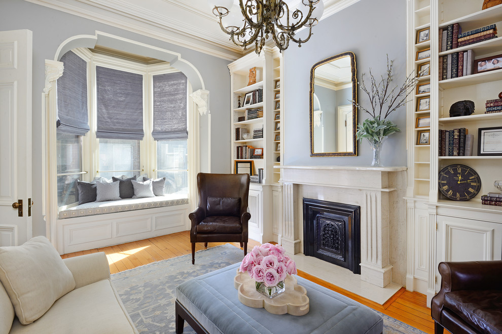 На фото: гостиная комната в классическом стиле с с книжными шкафами и полками, серыми стенами, паркетным полом среднего тона и стандартным камином с