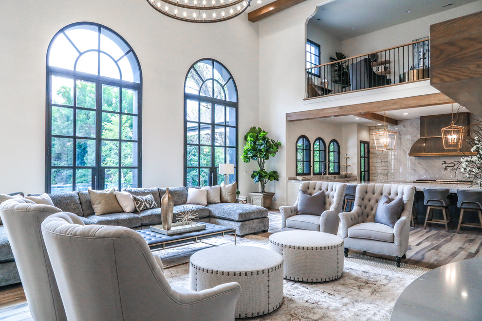 This is an example of a large mediterranean open plan games room in Salt Lake City with beige walls, ceramic flooring, a two-sided fireplace, a stone fireplace surround, a wall mounted tv and brown floors.