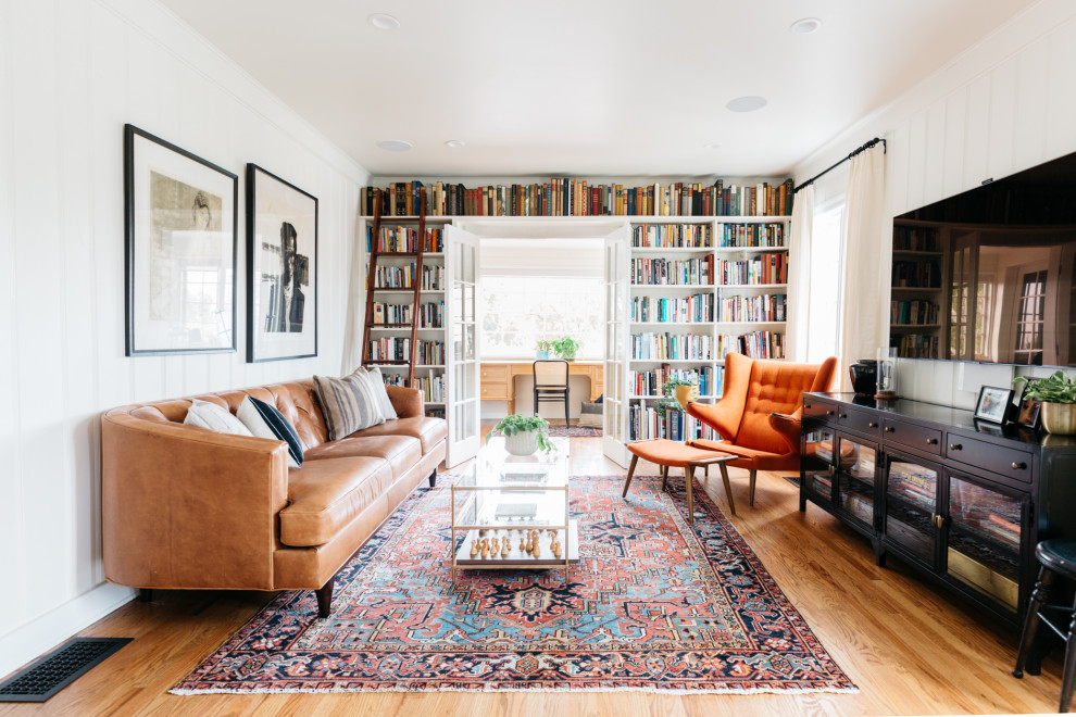 Abgetrenntes Klassisches Wohnzimmer mit weißer Wandfarbe, braunem Holzboden, TV-Wand und braunem Boden in Los Angeles