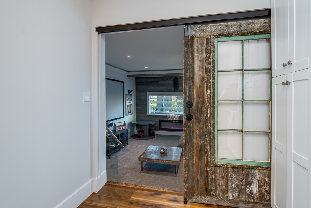 This is an example of a medium sized modern enclosed games room in Vancouver with multi-coloured walls, carpet, a ribbon fireplace, a wooden fireplace surround, a wall mounted tv and beige floors.