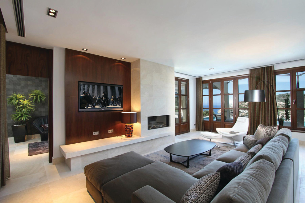 На фото: большая открытая гостиная комната:: освещение в стиле модернизм с белыми стенами, полом из известняка, горизонтальным камином, фасадом камина из плитки, телевизором на стене и бежевым полом с