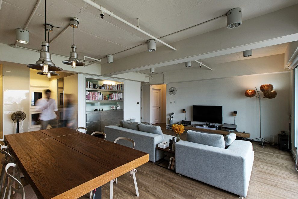 Modelo de sala de estar abierta industrial con paredes blancas, suelo de madera en tonos medios y televisor independiente