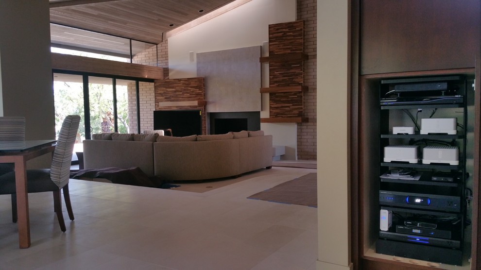 Cette image montre une grande salle de séjour design fermée avec un mur marron, un sol en carrelage de céramique, une cheminée standard, un manteau de cheminée en métal et un téléviseur fixé au mur.