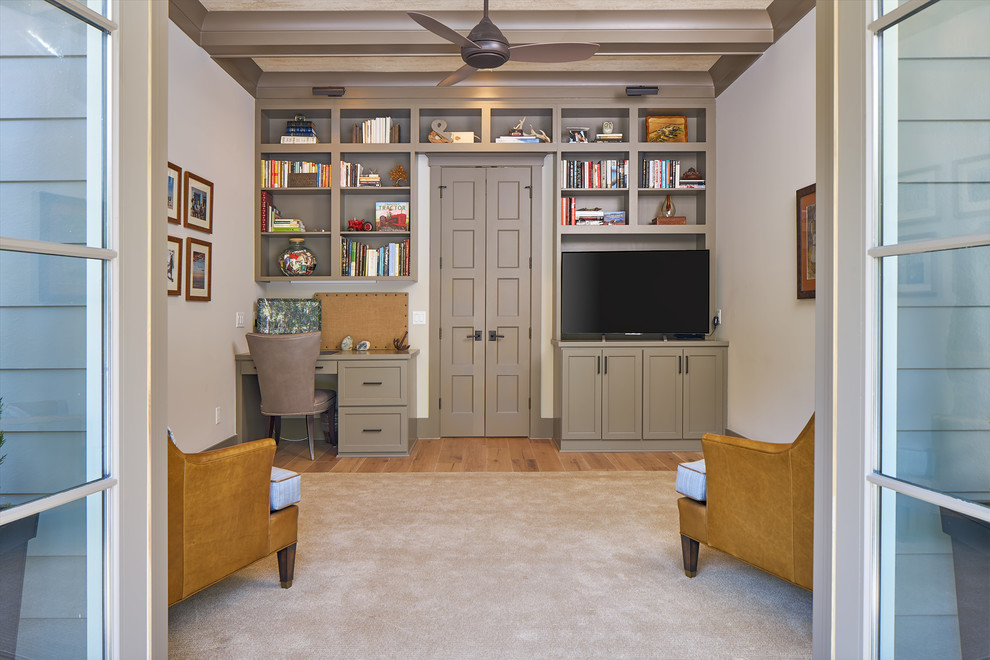 Modelo de sala de estar con biblioteca cerrada clásica renovada de tamaño medio con paredes grises, suelo de madera en tonos medios y pared multimedia