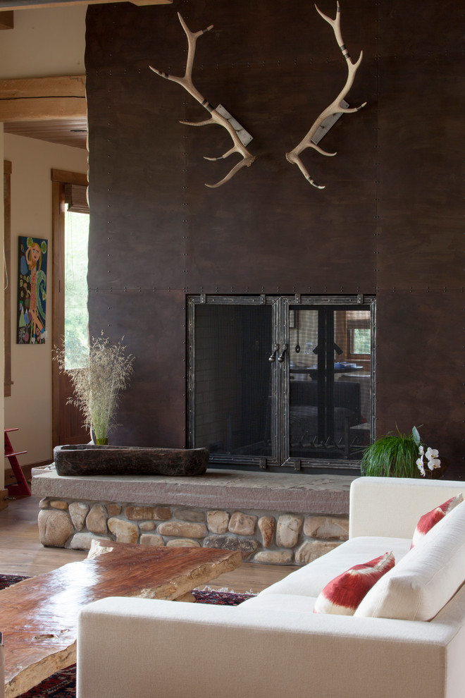 Mittelgroßes, Offenes Uriges Wohnzimmer mit beiger Wandfarbe, hellem Holzboden, Kamin und Kaminumrandung aus Metall in Sonstige