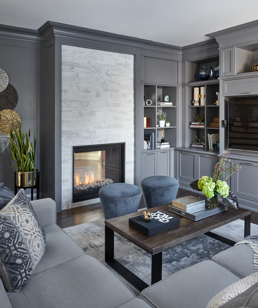 Идея дизайна: открытая гостиная комната среднего размера в стиле неоклассика (современная классика) с серыми стенами, темным паркетным полом, двусторонним камином, фасадом камина из камня, телевизором на стене и коричневым полом