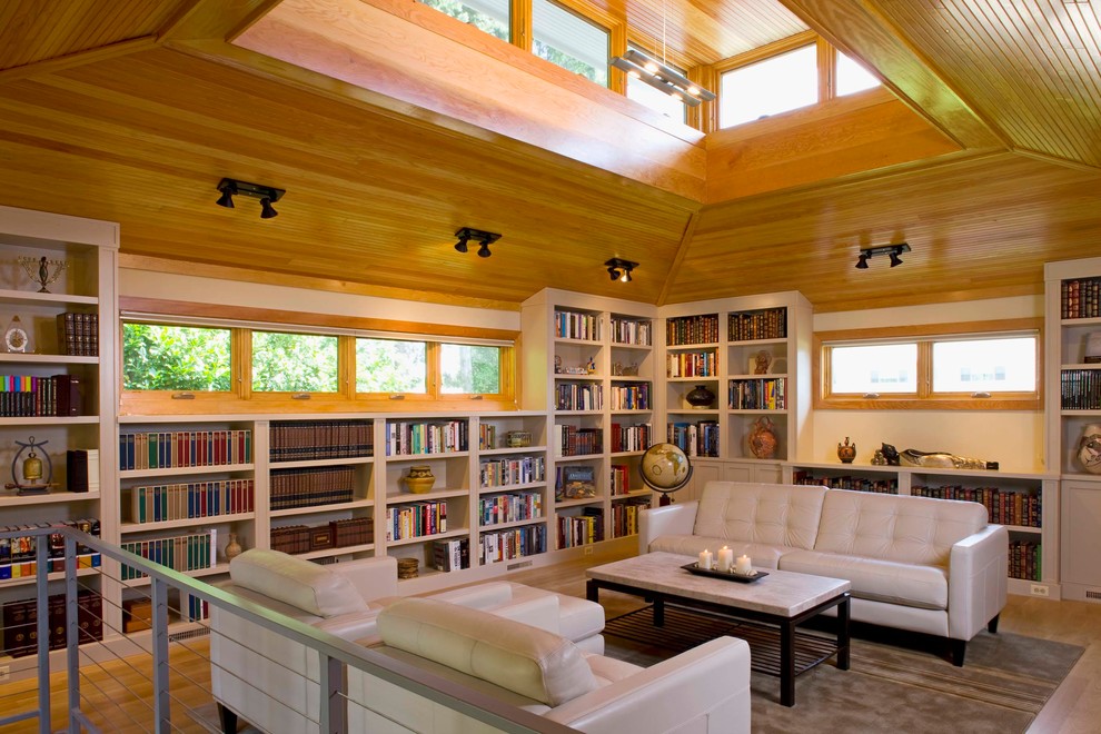 Esempio di un soggiorno design stile loft con libreria, pareti beige e pavimento in legno massello medio
