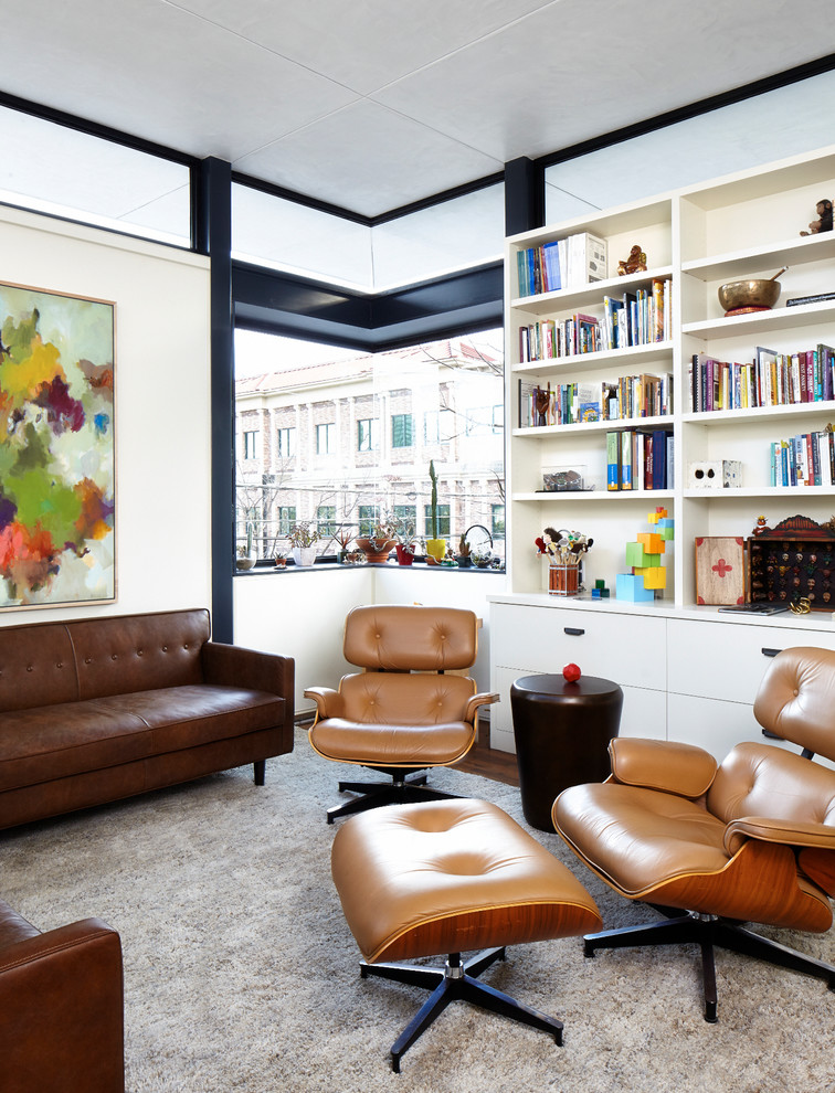 Cette photo montre une salle de séjour tendance avec une bibliothèque ou un coin lecture, un mur blanc et parquet foncé.