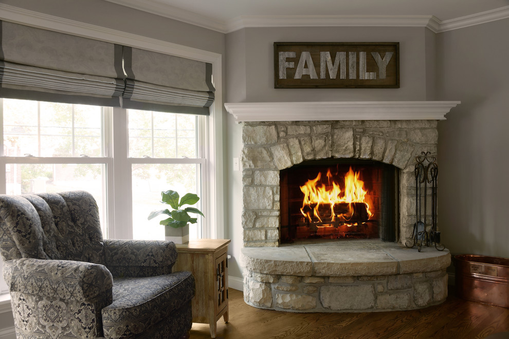セントルイスにあるお手頃価格の中くらいなトランジショナルスタイルのおしゃれな独立型ファミリールーム (グレーの壁、無垢フローリング、コーナー設置型暖炉、石材の暖炉まわり) の写真