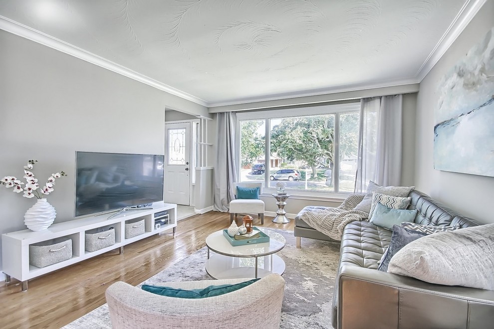 Diseño de sala de estar abierta actual de tamaño medio sin chimenea con paredes grises, suelo de madera en tonos medios y televisor independiente