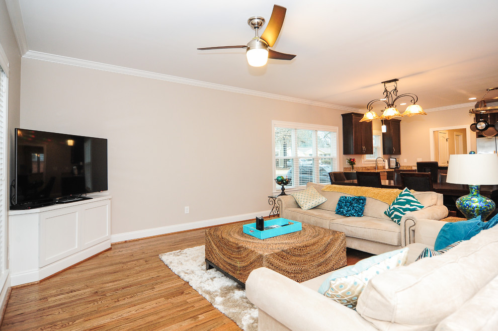 Esempio di un soggiorno classico aperto con pareti beige, pavimento in legno massello medio, nessun camino e TV autoportante