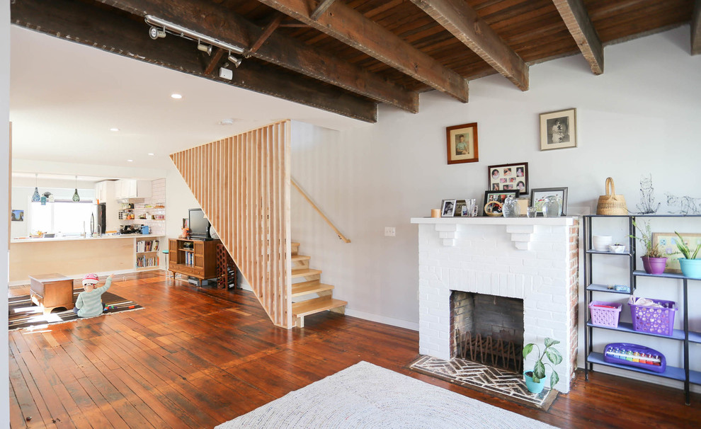 Modelo de sala de estar abierta vintage pequeña con suelo de madera en tonos medios, marco de chimenea de ladrillo y alfombra