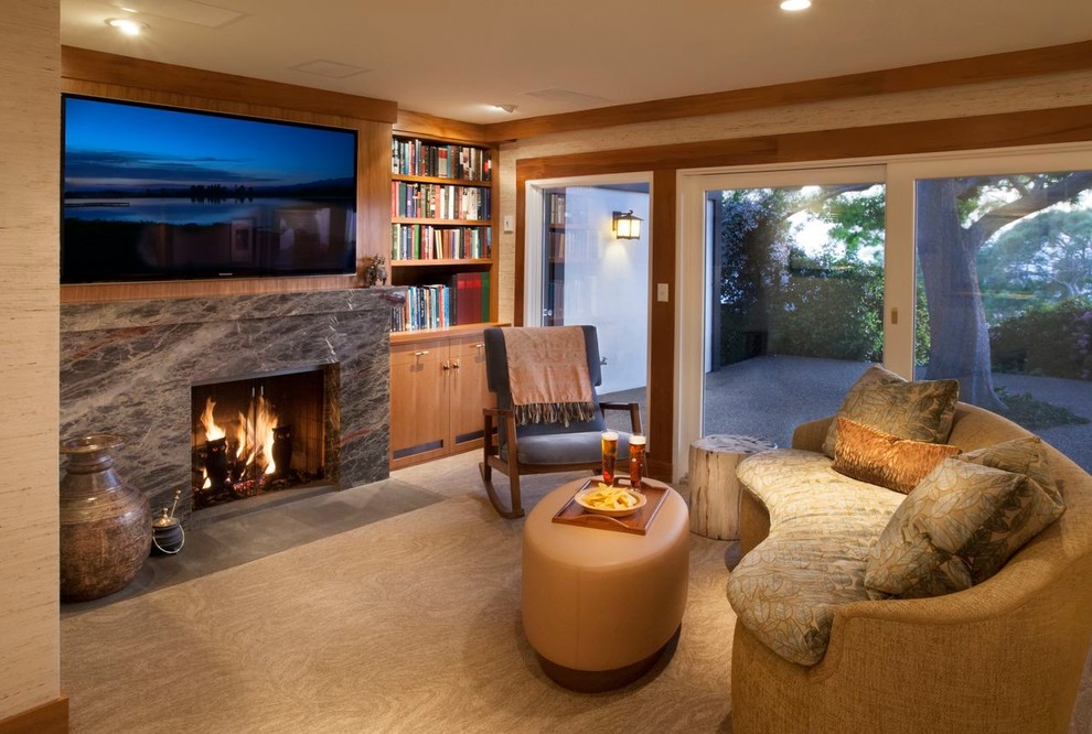 Cette photo montre une salle de séjour tendance avec une bibliothèque ou un coin lecture, un mur beige, moquette, une cheminée standard, un manteau de cheminée en pierre et un téléviseur fixé au mur.