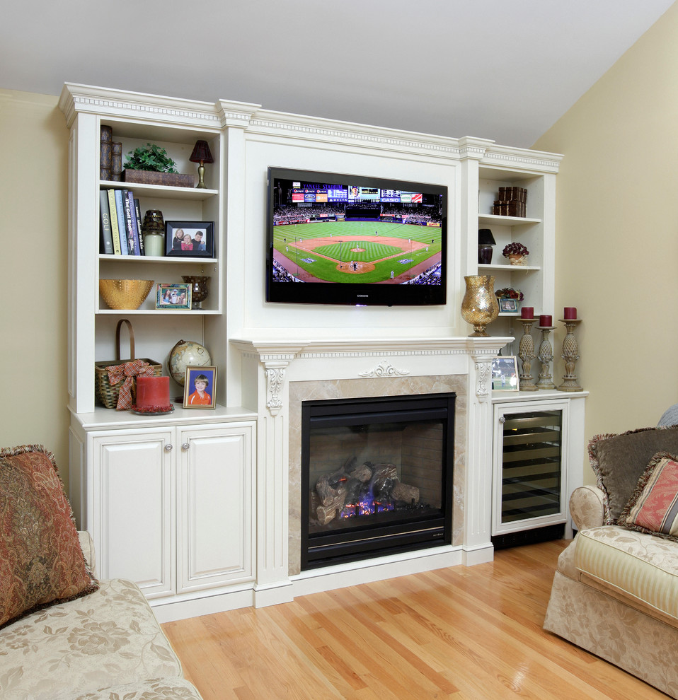 Mid-sized elegant enclosed light wood floor game room photo in New York with beige walls, a standard fireplace, a wall-mounted tv and a wood fireplace surround