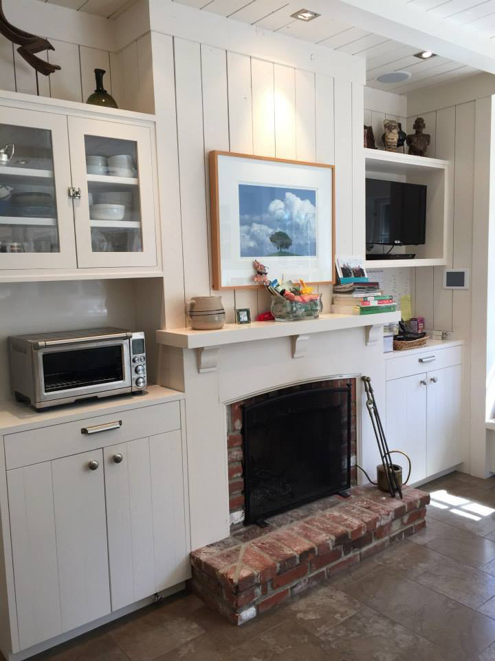 サンタバーバラにあるお手頃価格の広いトランジショナルスタイルのおしゃれなオープンリビング (ホームバー、白い壁、トラバーチンの床、標準型暖炉、漆喰の暖炉まわり、埋込式メディアウォール) の写真