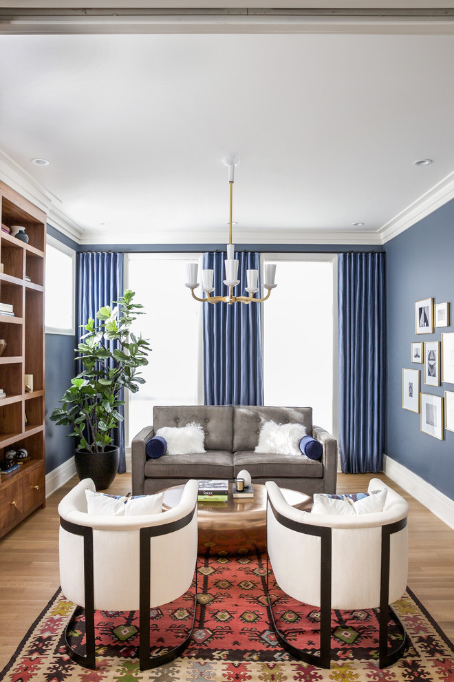 Cette image montre une salle de séjour traditionnelle avec une bibliothèque ou un coin lecture, un mur bleu, un sol en bois brun et un sol marron.